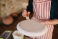 Close up of potter`s hands making ornament on ceramic product. Plate in male`s hands. Young artist Royalty Free Stock Photo