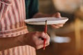 Close up of potter`s hands making ornament on ceramic product. Plate in male`s hands. Young artist Royalty Free Stock Photo