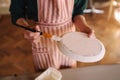 Close up of potter`s hands making ornament on ceramic product. Plate in male`s hands. Young artist Royalty Free Stock Photo