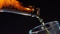 Close up of pouring beer from the glass brown bottle into the glass. Video. Pouring alcoholic drink isolated on black Royalty Free Stock Photo