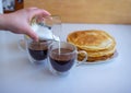 Close up pouring milk from a glass into a mug with freshly brewed coffee Royalty Free Stock Photo