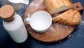 Close up of pouring milk in white cup in a wooden background next to bread.