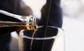 Close-up Pouring soda from bottle into clear glass, Selective focus of fresh drink with blurry background with bright light Royalty Free Stock Photo