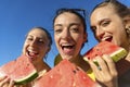 Close up pov portrait of three happy girls eating watermelon at the beach outdoors in summer time. friends having fun isolated on Royalty Free Stock Photo