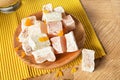 Close-up of a powdered turkish delight. Plate of fruit rahat lokum on a wooden background. Exotic confectionery sweets.