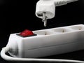 Close up of power button and plug from a white power strip on black background Royalty Free Stock Photo