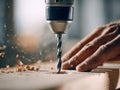Close-up of a powerful electric drill making precise holes in wooden plank with hand steadying the surface during carpentry work Royalty Free Stock Photo