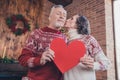 Close-up pphoto portrait couple celebrating winter holidays together keeping red heart postcard wife kissing husband