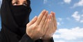 Close up of praying muslim woman in hijab over sky