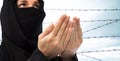 Close up of praying muslim woman over barb wire