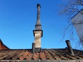 Close up of Prefabricated building roof with industrial black chimney under blue sky. Architecture and construction detail