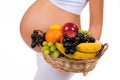 Close-up of a pregnant belly and a basket of exotic fruits.