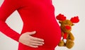 Close up on pregnant belly, dressed in red.