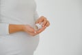 Close up on pregnant belly with medicine..Woman expecting a baby dressed in white holding pills. Taking drugs or vitamins during Royalty Free Stock Photo