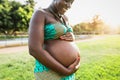 Close up pregnant belly of young African woman in park during sunset time Royalty Free Stock Photo