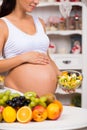 Close-up of a pregnant tummy with fresh fruit and plate of salad. Healthy pregnancy, diet and vitamins