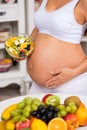 Close-up of a pregnant tummy with fresh fruit and plate of salad. Royalty Free Stock Photo