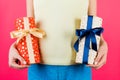 Close up of pregnant woman in colorful home clothing holding two gift boxes at pink background. Is it a boy or a girl Expecting