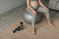 Close up pregnant woman drink water from bottle breathe having rest on fitball. Royalty Free Stock Photo