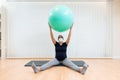 Close up of a pregnant woman with face mask sitting on floor doing pilates exercises with a ball Royalty Free Stock Photo