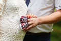 Close-up of a pregnant woman and her husband holding baby shoes