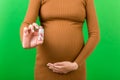 Close up of pregnant woman holding a bottle of pills against her belly at colorful background with copy space. Taking medication Royalty Free Stock Photo