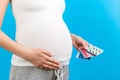 Close up of pregnant woman holding different blisters with pills at colorful background with copy space. Taking supplement during Royalty Free Stock Photo