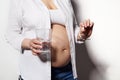 Close-up pregnant woman holding glass of water and medical pill with vitamins and minerals to take during pregnancy Royalty Free Stock Photo