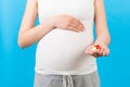 Close up of pregnant woman holding a pile of pills at colorful background with copy space. Taking medications and vitamins during Royalty Free Stock Photo