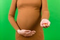 Close up of pregnant woman holding a pile of pills at colorful background with copy space. Taking medications and vitamins during