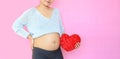 Close-up pregnant woman holding red heart pillow at belly isolated on pink background with copy space Royalty Free Stock Photo