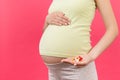 Close up of pregnant woman holding a stack of vitamin pills in her hand at colorful background with copy space. Medicine concept