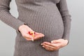 Close up of pregnant woman holding a stack of vitamin pills in her hand at colorful background with copy space. Medicine concept