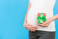 Close up of pregnant woman in home clothing holding gift box at blue background. Baby surprise concept. Happy pregnancy. Copy Royalty Free Stock Photo