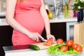 Close up pregnant woman with knife on kitchen cuts tomato Royalty Free Stock Photo