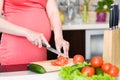 Close up pregnant woman with knife on kitchen cuts vegetables Royalty Free Stock Photo