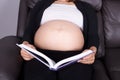 Close up pregnant woman lying on sofa and reading book Royalty Free Stock Photo