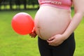 Close-up of pregnant woman mother belly, hold red balloon keep healthy positive attitude hope love concept Royalty Free Stock Photo