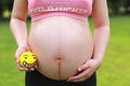 Close-up of pregnant woman mother belly, hold yellow toy smile emoji keep healthy positive attitude Royalty Free Stock Photo