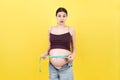 Close up of a pregnant woman in opened jeans measuring her belly with a tape measure at colorful background with copy space. Royalty Free Stock Photo