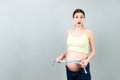 Close up of a pregnant woman in opened jeans measuring her belly with a tape measure at colorful background with copy space.