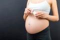 Close up of pregnant woman opening a bottle of pills at colorful background with copy space. Taking medicine during pregnancy Royalty Free Stock Photo