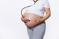 Close-up pregnant woman puts a stethoscope on her belly and listens to heartbeat of her baby in womb. Fetus development Royalty Free Stock Photo