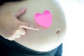 Close up of pregnant woman`s belly has a sticky note heart shaped. pregnancy and maternity concept. mother and baby concept. Royalty Free Stock Photo