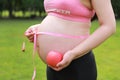 Close-up of pregnant woman mother belly, she is using a ruler to measure waistline an red apple beside keep healthy do exercise Royalty Free Stock Photo