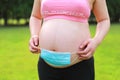 Close-up of pregnant woman mother belly,hands with mask on belly COVID-19 virus outbreak protect baby from hurting