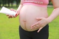 Close-up of pregnant woman mother belly, apply lotion prevent stretch marks over grass lawn meadow sunset outdoor nature summer