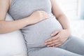 Close up of pregnant woman sitting on the bed and touching her belly at home. Selective focus. Royalty Free Stock Photo