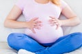 Close up of pregnant woman sitting on couch touching her belly Royalty Free Stock Photo