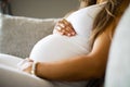 Close-up of pregnant woman sitting in sofa with her hands at belly